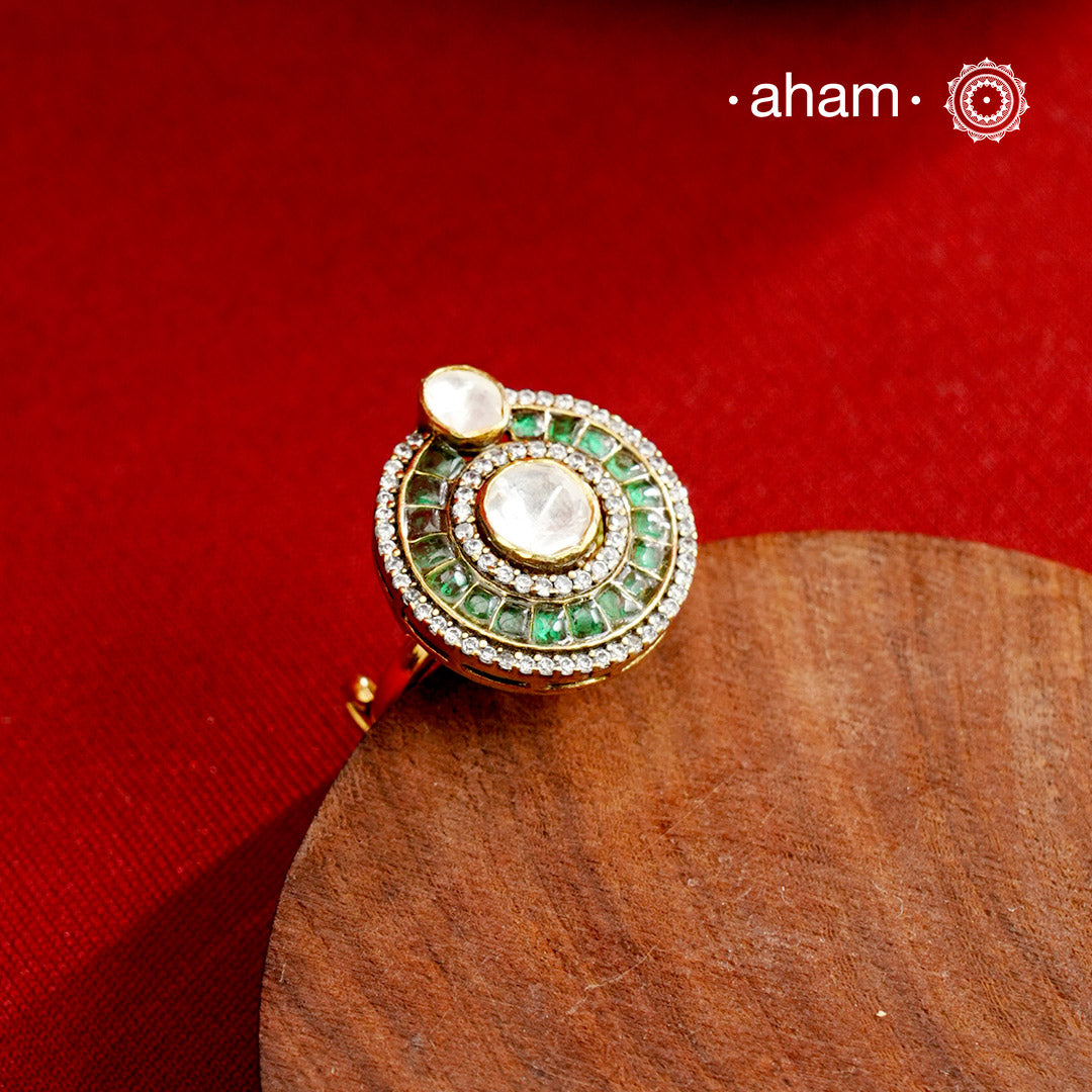 This exquisite ring features a dazzling moissanite center stone, surrounded by vibrant green emerald-like stones that enhance its elegance. Expertly crafted in 92.5% sterling silver with a fin gold polish. Perfect for those seeking a sophisticated accessory that combines timeless design with exceptional craftsmanship.
