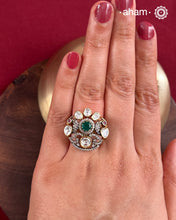 Crafted from 92.5% sterling silver with a rich gold polish, this ring showcases a captivating green emerald-like center stone. Surrounding it, moissanite stones add exceptional sparkle and brilliance, enhancing the ring’s luxurious appeal. Designed with precision, this piece offers a perfect blend of elegance and glamour for discerning jewellery enthusiasts.