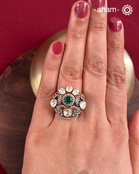 Crafted from 92.5% sterling silver with a rich gold polish, this ring showcases a captivating green emerald-like center stone. Surrounding it, moissanite stones add exceptional sparkle and brilliance, enhancing the ring’s luxurious appeal. Designed with precision, this piece offers a perfect blend of elegance and glamour for discerning jewellery enthusiasts.