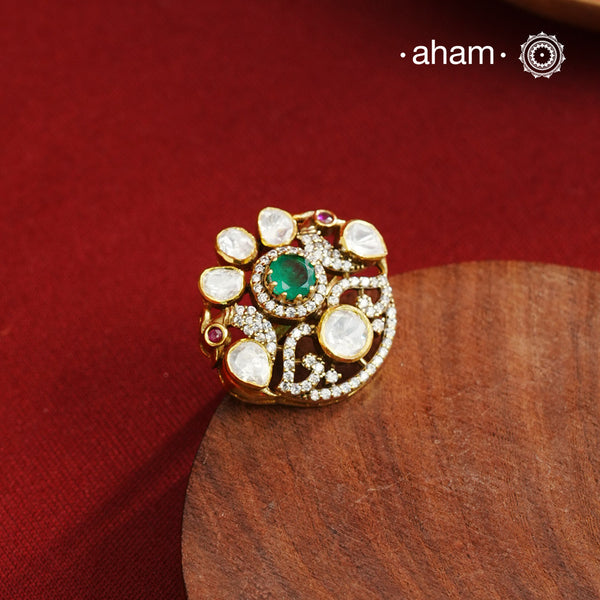 Crafted from 92.5% sterling silver with a rich gold polish, this ring showcases a captivating green emerald-like center stone. Surrounding it, moissanite stones add exceptional sparkle and brilliance, enhancing the ring’s luxurious appeal. Designed with precision, this piece offers a perfect blend of elegance and glamour for discerning jewellery enthusiasts.