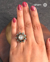 This exquisite ring features a dazzling moissanite ring with an elegant flower design, accented by green stones. Crafted from 92.5% sterling silver and enhanced with a refined gold polish, for a luxurious finish. Perfect for those seeking a sophisticated blend of classic craftsmanship and contemporary style.
