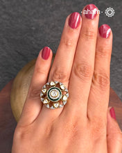 This exquisite ring features dazzling moissanites set within an elegant flower design, accented by vibrant deep green meena work. Crafted from 92.5% sterling silver and enhanced with a refined gold polish, for a luxurious finish. Perfect for those seeking a sophisticated blend of classic craftsmanship and contemporary style.