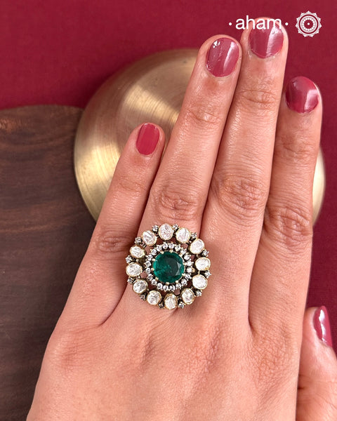 Crafted from 92.5% sterling silver with a rich gold polish, this ring showcases a captivating green emerald-like center stone. Surrounding it, moissanite stones add exceptional sparkle and brilliance, enhancing the ring’s luxurious appeal. Designed with precision, this piece offers a perfect blend of elegance and glamour for discerning jewellery enthusiasts.