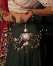 Rooted in the traditions of India's tribal communities, this handcrafted Silver Kamarbandh is a striking expression of heritage and craftsmanship. At its heart lies an intricately carved peacock motif, meticulously handcrafted using the traditional Chilai work technique, surrounded by hand-cut leaf motifs and cascading silver ghungroos. Every element comes together to create a piece that moves gracefully with every step.