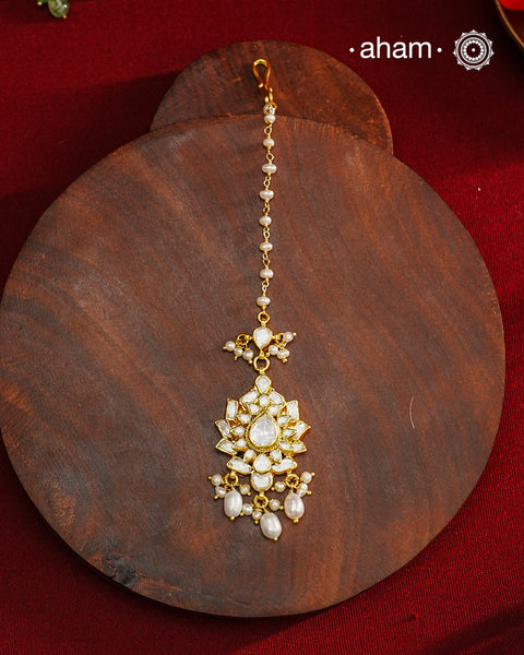 Crafted from 92.5% sterling silver with a fine gold polish finish, this maang tikka features brilliant moissanite stones that enhance its radiant appeal. Designed for enduring shine and elegance, it is an ideal accessory to complement your ensemble on special occasions.