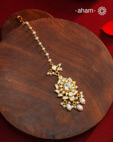 Crafted from 92.5% sterling silver with a fine gold polish finish, this maang tikka features brilliant moissanite stones that enhance its radiant appeal. Designed for enduring shine and elegance, it is an ideal accessory to complement your ensemble on special occasions.