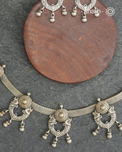 The Mewad Silver Neckpiece &amp; Earrings Set showcases expertly crafted silver paired with delicate ghungroos, designed to complement professional attire effortlessly. This lightweight and elegant set brings a refined cultural touch to your workwear, ensuring comfort and sophisticated style throughout your busy day.