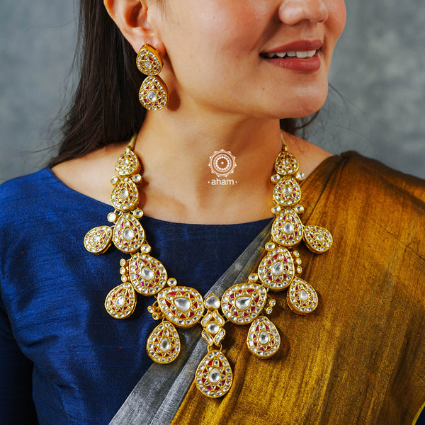 Make a sophisticated style statement this festive season with our beautiful gold polish neckpiece and earrings set. Crafted using traditional techniques in silver with intricate drops in red and kundan setting. Perfect for intimate weddings and upcoming festive celebrations.