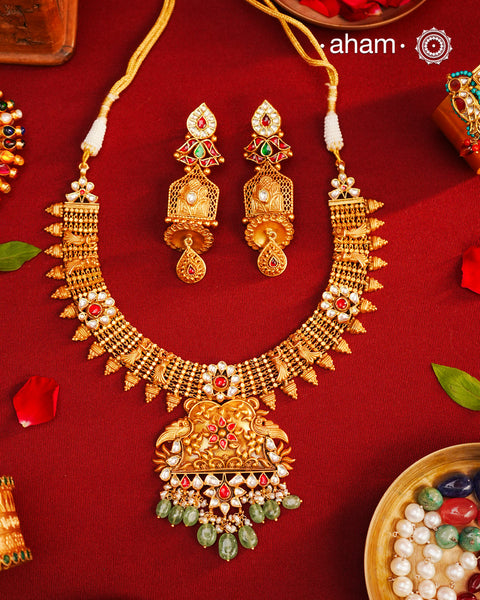 This Kundan Pearl Gold Polish Silver Neckpiece &amp; Earrings Set from our Heritage collection showcases intricate traditional designs, meticulously crafted in 92.5 silver with a stunning gold polish and exquisite kundan work. Perfect for modern brides seeking a touch of timeless elegance.