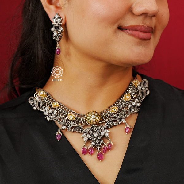 Expertly crafted in silver, the Noori Dual Tone Silver Set is a modern heirloom piece exuding sophistication. Adorned with pink stones and subtle kundan highlights, its Victorian design with marcasite setting adds a touch of elegance. Elevate your style with this timeless jewellery set.