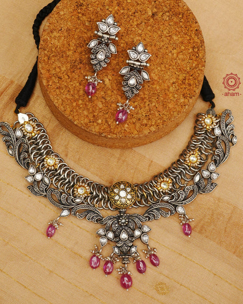 Expertly crafted in silver, the Noori Dual Tone Silver Set is a modern heirloom piece exuding sophistication. Adorned with pink stones and subtle kundan highlights, its Victorian design with marcasite setting adds a touch of elegance. Elevate your style with this timeless jewellery set.