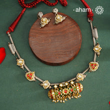 Expertly crafted in 92.5% silver, the Noori Dual Tone Silver Neckpiece &amp; Earrings Set blends traditional South Indian amulet design with contemporary elegance. Featuring intricate kemp work and gold polish at its center, the set is adorned with multiple small silver amulets along the chain and delicate pearl highlights. This dual-tone ensemble offers a refined balance of heritage and modernity, making it a timeless addition to any collection.