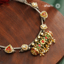 Expertly crafted in 92.5% silver, the Noori Dual Tone Silver Neckpiece &amp; Earrings Set blends traditional South Indian amulet design with contemporary elegance. Featuring intricate kemp work and gold polish at its center, the set is adorned with multiple small silver amulets along the chain and delicate pearl highlights. This dual-tone ensemble offers a refined balance of heritage and modernity, making it a timeless addition to any collection.