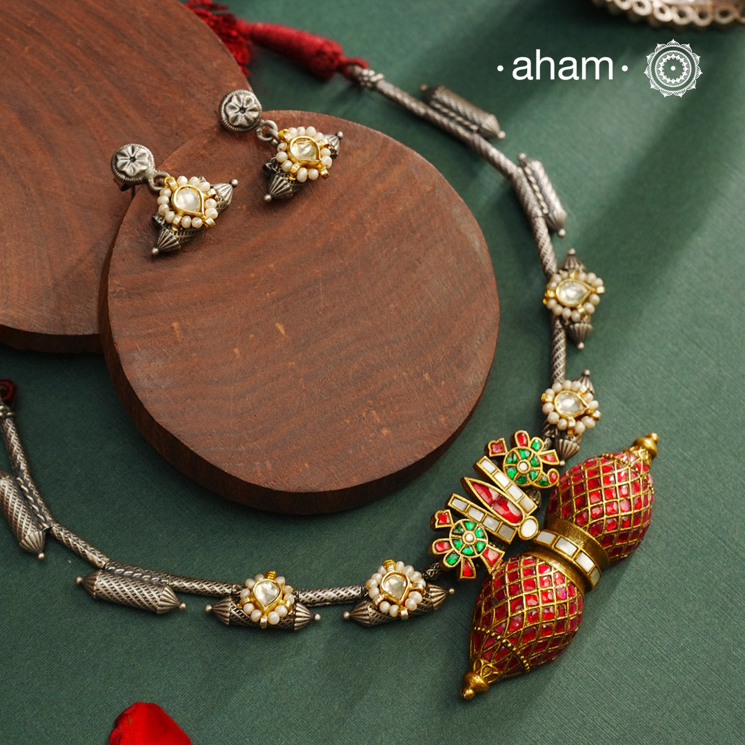 Expertly crafted in 92.5% silver, the Noori Dual Tone Silver Neckpiece & Earrings Set blends traditional South Indian amulet design with contemporary elegance. Featuring intricate kemp work and gold polish at its center, the set is adorned with multiple small silver amulets along the chain and delicate pearl highlights. This dual-tone ensemble offers a refined balance of heritage and modernity, making it a timeless addition to any collection.