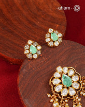 A celebration of classic craftsmanship, this pendant and earring set features a striking green center stone framed by shimmering moissanites in an intricate floral design and laced with pearls.Crafted in 92.5 silver and finished in gold polish, it is a versatile piece that effortlessly elevates festive, wedding, and occasion wear.