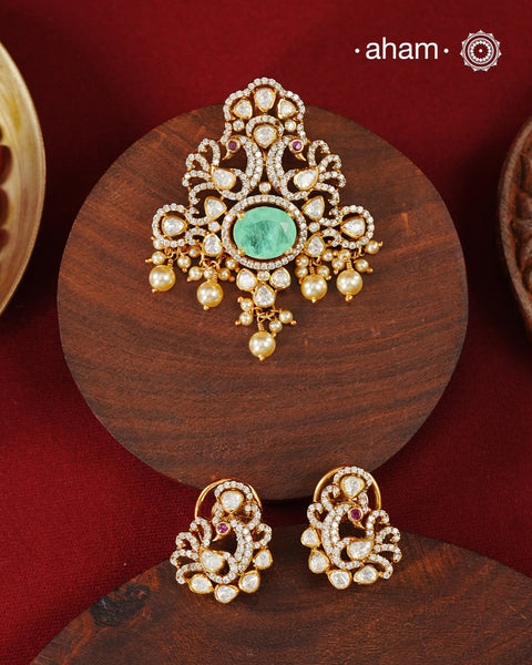Crafted in 92.5 sterling silver with an elegant gold polish finish, this pendant and earring set features sparkling moissanite stones surrounding a lustrous green centre stone. Timeless yet striking, it is designed to add effortless sophistication to special occasions.