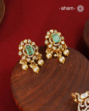 Crafted in 92.5 sterling silver with an elegant gold polish finish, this pendant and earring set features sparkling moissanite stones surrounding a lustrous green centre stone. Timeless yet striking, it is designed to add effortless sophistication to special occasions.