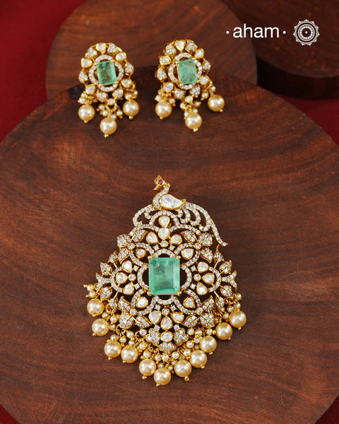 Crafted in 92.5 sterling silver with an elegant gold polish finish, this pendant and earring set features sparkling moissanite stones surrounding a lustrous green centre stone. Timeless yet striking, it is designed to add effortless sophistication to special occasions.