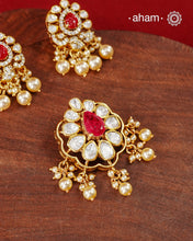A celebration of classic craftsmanship, this pendant and earring set features a striking ruby-hued center stone framed by shimmering moissanites in an intricate floral design and laced with pearls.Crafted in 92.5 silver and finished in gold polish, it is a versatile piece that effortlessly elevates festive, wedding, and occasion wear.