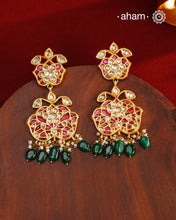 These intricately designed silver earrings are adorned with radiant Kundan, vibrant Kemp, and gleaming Emeralds, all beautifully complemented by lustrous Pearls. Finished with a luxurious Gold Polish, these earrings exude timeless elegance and are a must-have addition to any jewellery collection. Perfect for weddings, festive occasions, or adding a touch of heritage charm to your everyday look.
