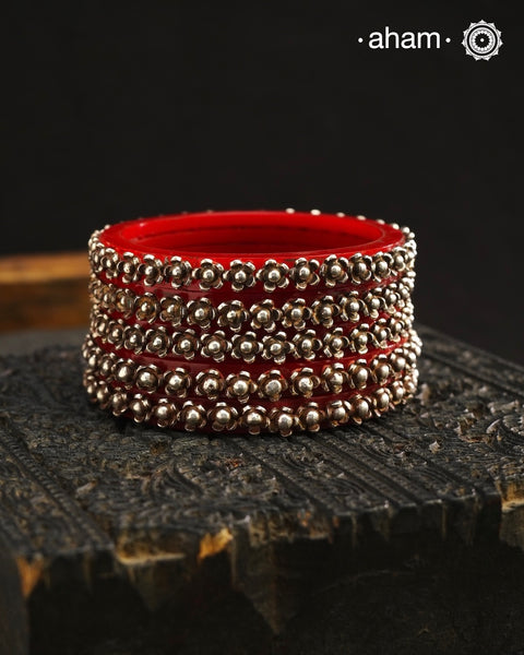 Beautiful tribal silver Bangles. Perfectly crafted silver flowers set on red plastic bangles. Comes as a set of 2 Bangles.