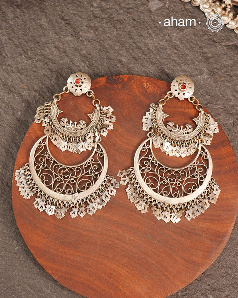 This exquisite two-layer silver chandbali earring blends traditional charm with contemporary design, creating a striking statement piece. Crafted with intricate detailing, it harmonizes classic elements and modern aesthetics, making it perfect for elevating any ensemble with elegance. Ideal for those who appreciate timeless artistry