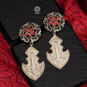 Statement Silver Anchor earrings crafted by our skilful artisans. Comes with intricate floral work and red stone highlight. 
