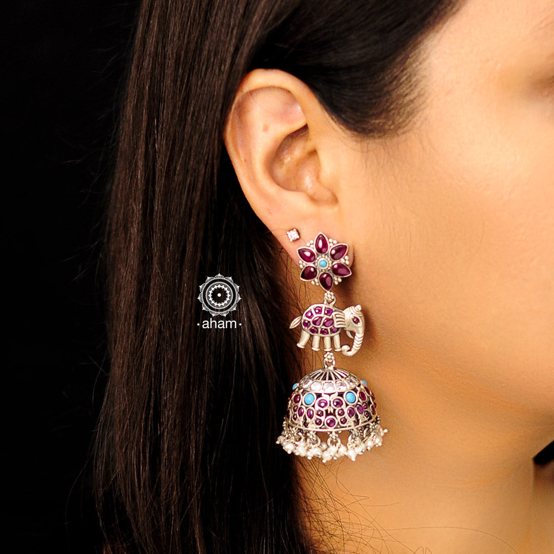 Handcrafted statement Nrityam jhumkie earrings in 92.5 sterling silver. Elegant elephant and floral motifs, enhanced with kemp & turquoise coloured stone setting and hanging cultured pearls. 