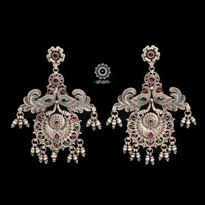 Mewad double peacock earrings handcrafted in 92.5 sterling silver with green and maroon stones. An ode to the glorious state of Rajasthan. Perfect pair of elegant danglers for your ethnic outfits. 