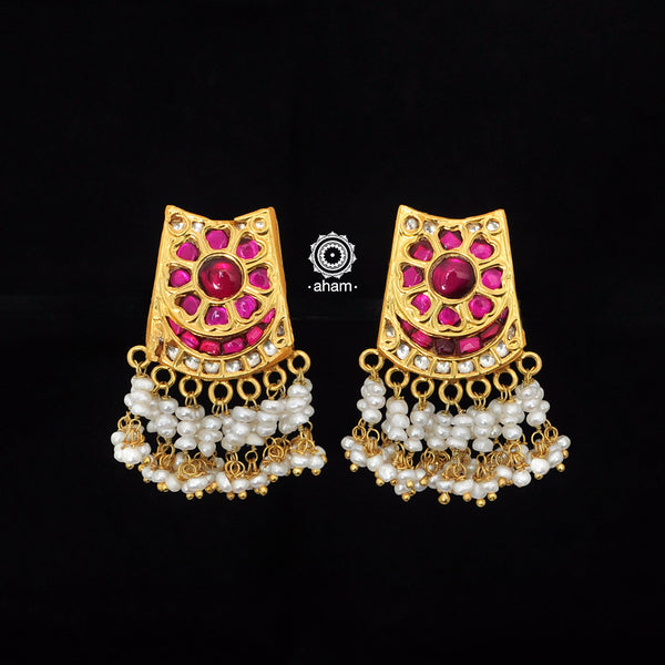 These silver earrings, adorned with intricate Kundan work and a gold polish, are laced with delicate cultured pearls, making them an ideal choice for festive occasions.