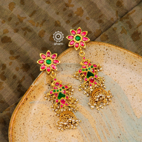 Vibrant gold polish fish jhumkie earrings with dangling cultured pearls. Handcrafted in 92.5 sterling silver with rani pink & green coloured stone setting. This piece strikes the perfect balance of tradition and new age simplicity. 