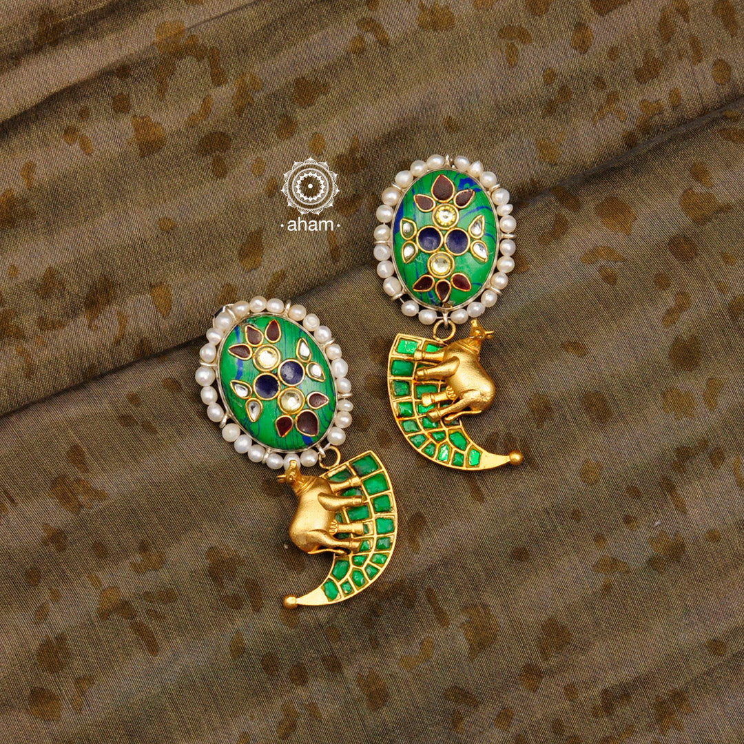 Handcrafted Noori two tone tiger claw silver earrings with green semi precious stone setting. Created in 92.5 sterling silver with a Kamadhenu (an auspicious sacred cow in the Hindu mythology) motif and embellished cultured pearls. Designed keeping modern sensibilities in mind, perfect for special occasions and festivities. 