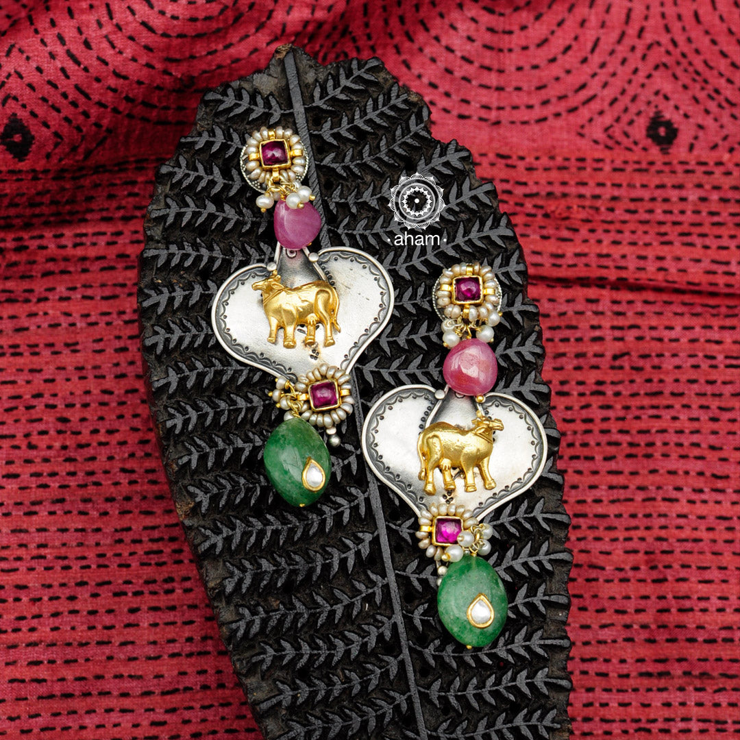 Handcrafted Noori two tone earrings in 92.5 sterling silver. With beautiful Kamadhenu (an auspicious sacred cow in the Hindu mythology) motif and vibrant semi precious stones. Style this up with your favourite ethnic or fusion outfit.