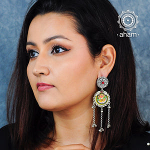 Silver Earring with an intricate miniature hand painted Ganesha Motif in vibrant colours. Enclosed with a glass top, these are hand painted one of a kind wearable art pieces. These shoulder duster earrings are bound to make a statement 