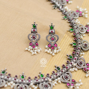 Make a sophisticated style statement this festive season in this nrityam heart shaped neckpiece and earring set. Handcrafted in 92.5 sterling silver using traditional artistry with green and maroon Kemp stone setting. Perfect for intimate weddings and upcoming festive celebrations. 