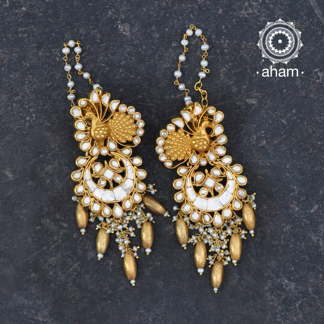 Statement gold polish chandelier earrings with elegant peacock motif. Handcrafted using traditional techniques in silver with kundan work and dangling cultured pearls. Perfect for intimate weddings and upcoming festive celebrations.