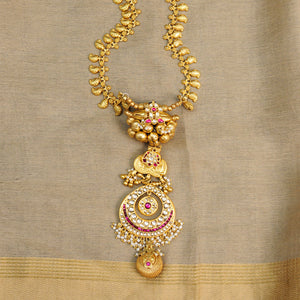 Make a sophisticated style statement this festive season with this elegant neckpiece with a crescent drop pendant centre. Necklace with dainty paisley motifs and tribal gold polish amulets with jadau kundan work. Crafted using traditional techniques in silver with gold polish and cultured pearls. Perfect for intimate weddings and upcoming festive celebrations.