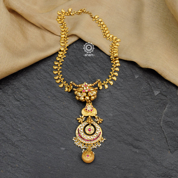 Make a sophisticated style statement this festive season with this elegant neckpiece with a crescent drop pendant centre. Necklace with dainty paisley motifs and tribal gold polish amulets with jadau kundan work. Crafted using traditional techniques in silver with gold polish and cultured pearls. Perfect for intimate weddings and upcoming festive celebrations.