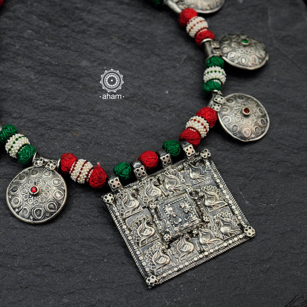 Handcrafted tribal silver neckpiece with intricate floral and peacock motifs. Beautiful tribal silver pieces threaded together including red and green work. This necklace truly exemplifies the continuity of the traditional prototypes.