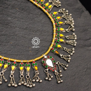 Handcrafted tribal glass silver neckpiece with statement ghungroos. Created by threading together multiple tribal pieces with green amd red stones giving it a vibrant look. This necklace truly exemplifies the continuity of the traditional designs. 