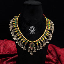 Handcrafted tribal glass silver neckpiece with statement ghungroos. Created by threading together multiple tribal pieces with green amd red stones giving it a vibrant look. This necklace truly exemplifies the continuity of the traditional designs. 