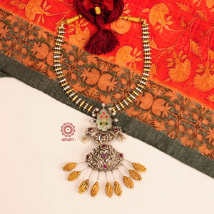 We thrive to bring alive traditional forms in new avatars. This Noori Dual tone neckpiece with inlay work green stone drop is crafted in 92.5 sterling silver using intricate nakshi work, studded with maroon spinel drops, cultured pearls. Perfect for intimate weddings and upcoming festive celebrations. 
