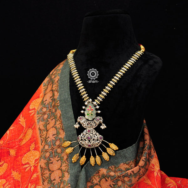 We thrive to bring alive traditional forms in new avatars. This Noori Dual tone neckpiece with inlay work green stone drop is crafted in 92.5 sterling silver using intricate nakshi work, studded with maroon spinel drops, cultured pearls. Perfect for intimate weddings and upcoming festive celebrations. 