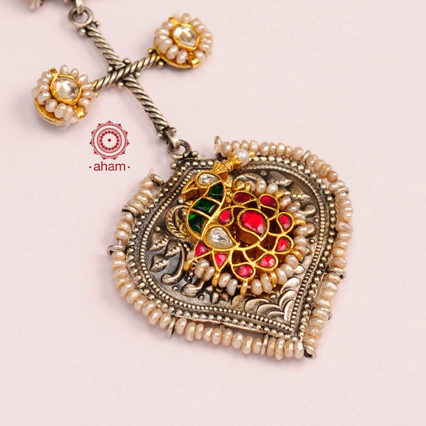 Noori two tone pearl chain neckpiece with elegant peacock motif in green and red kundan setting. Handcrafted in 92.5 sterling silver, looks great with your contemporary outfits.