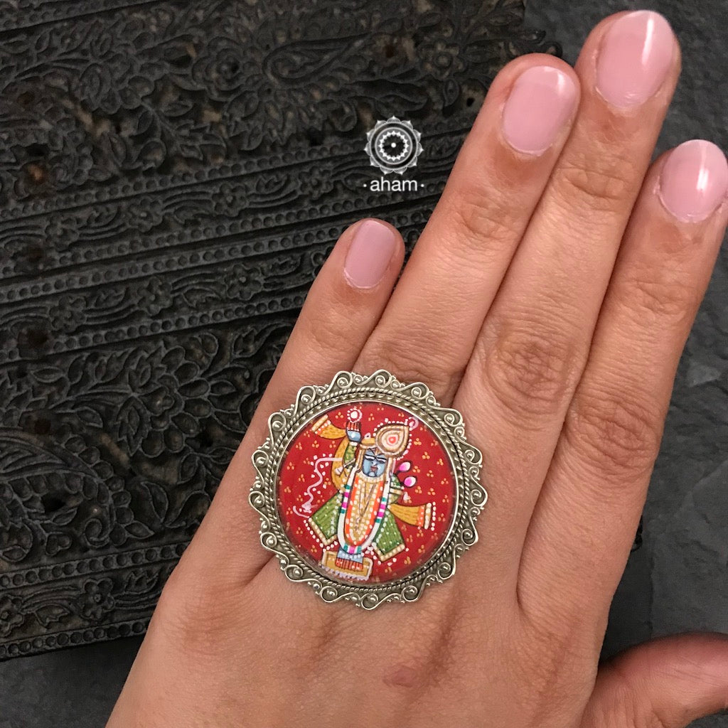 92.5 Sterling silver ring with an intricate hand painted Krishna motif in vibrant colours. Enclosed with a glass top and an adjustable ring band, these are one of a kind wearable art pieces.