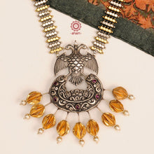We thrive to bringing alive traditional forms in new avatars. This Dual tone Gandaberunda neckpiece is crafted in 92.5 sterling silver using traditional techniques, studded with maroon spinel drops and cultured pearls. Perfect for intimate weddings and upcoming festive celebrations. 