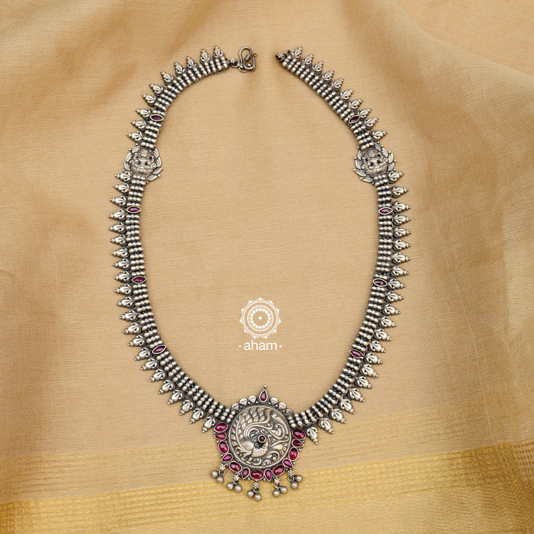 Make a sophisticated style statement this festive season in this nrityam peacock neckpiece. The necklace is crafted in 92.5 sterling silver using traditional artistry with intricate Goddess Lakshmi motif and maroon kemp stones. Perfect for intimate weddings and upcoming festive celebrations.
