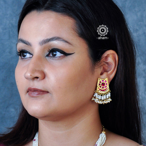 These silver earrings, adorned with intricate Kundan work and a gold polish, are laced with delicate cultured pearls, making them an ideal choice for festive occasions.